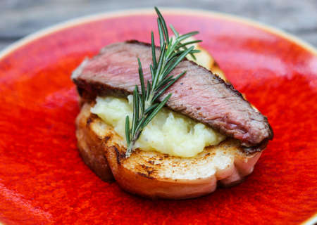 Grilled beef cooked medium-rare on creamy mash crostini.の写真素材