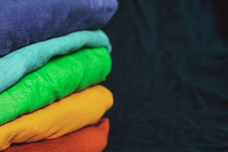 A stack of multicolored fabric without inscriptions. Background with folded clothes with blank space for information. T-shirts of different colorsの写真素材