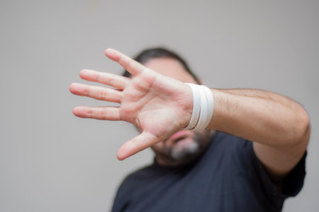 A frightened man with bracelets in the colors of the Bulgarian flag closes with an open palm. The man is trying to close and push himself away with his palm with an outstretched hand.の写真素材