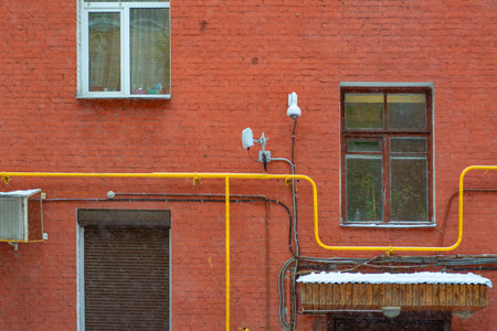 Brick wall of a building with yellow pipesの写真素材