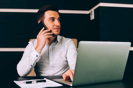 Attractive business man in smart casual wear sitting at his working place in officeの写真素材