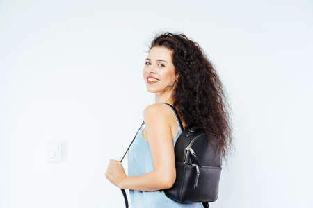 Young beautiful model with curly hair holding a backpackの写真素材