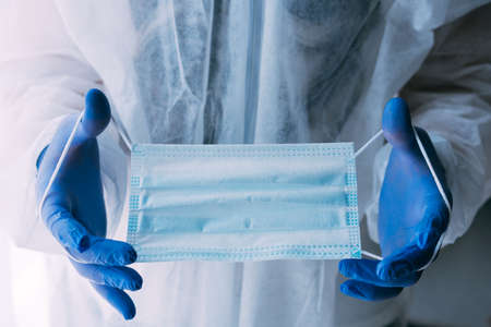 Man doctor or scientist waring protective suit holding a face maskの写真素材