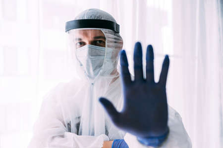 Man doctor or scientist waring protective suit, and face mask , STOP, hand gestureの写真素材