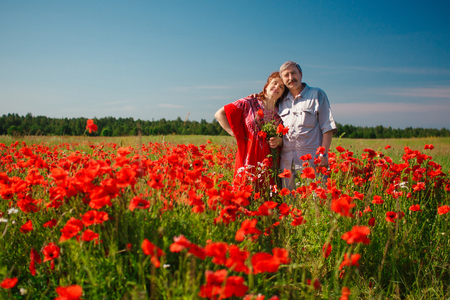 Happy old Elderly couple having fun, walking in a field with poppy flowers. Healthcare lifestyle senior couple relax in spring. People in love in summer time.の写真素材