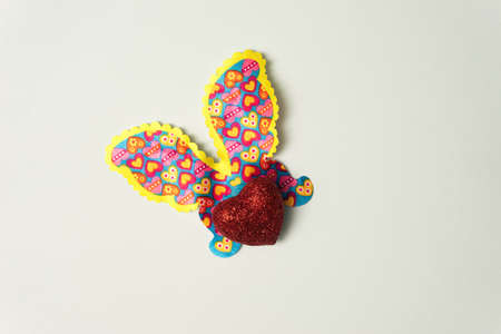 Glittery heart shaped body with butterfly wings - butterfly against nice light green background.