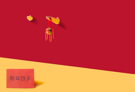 Two ox horns broke through deep Chinese red background. A horn with hanging embroidered ball symbol of good luck. Down deep yellow lucky envelope with Cantonese  characters greeting "Happy New Year."の写真素材