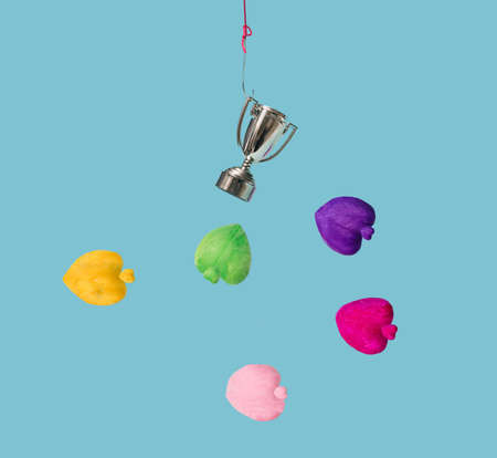A shiny trophy on fish hook surrounded by hearts in different colors. Blue water background.