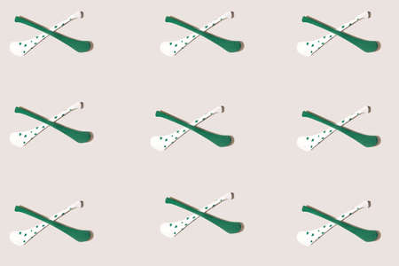 Pattern made of criss-crossed two hurly sticks â hurleys in green and white color with shamrock decoration.  Flat lay against beige background.の写真素材