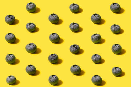 Minimalistic pattern of organic natural blueberries. Concept made on optimistic yellow background.の写真素材