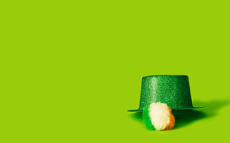 A green glittery hat on bright green background with pom pom with Irish flag colors. Copy space. Great for a St. Patrick's Day!の写真素材