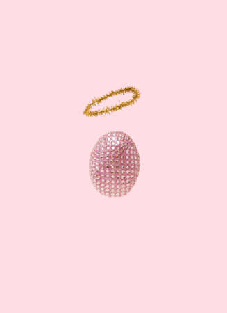 Easter concept. Sparkling disco egg with helo. Pastel pink background.の写真素材