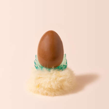 Chocolate egg on fluffy royal throne looks like minimal arrangement. Posh champagne background.の写真素材