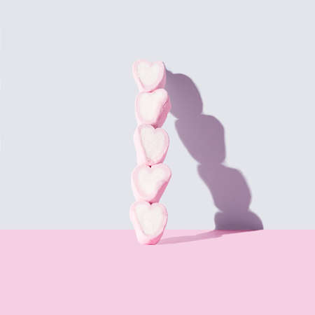 Five pink and white heart likes marshmallow on top of each other. Shadow on the wall, gray and pink...
