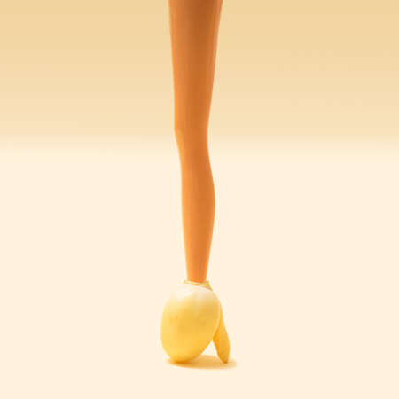 Girl toy leg in natural yellow eggplant on gradient ivory background.の写真素材
