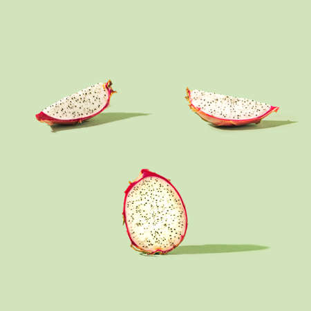 Concept created of slices and a half of fresh exotic dragon fruit on optimistic pastel green...