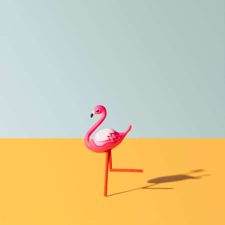 One pink flamingo toy looks like runing. Bright optimistic orange and light gray background.の写真素材