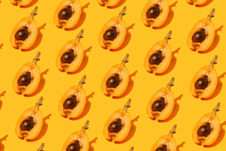Attractive pattern made of delightful tasty medlar fruits cuts on half. Splendid orange background.