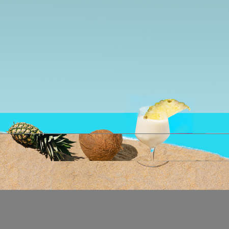 A fresh natural coconut,  organic pineapple and glass of pina colada cocktail on sandy beach,...