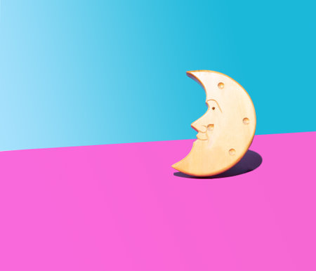 Wooden crescent moon face shape concept. Arrangement against purple and light blue backgroundの写真素材