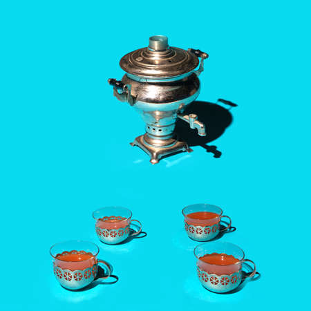 Tea enjoyer concept. Antique silver samovar self brewer with four tea cups against blue background.の写真素材
