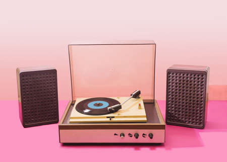 Gramophone record player from sixties with speakers. Turntable for single vinyl with pink bottom with light pink background.の写真素材