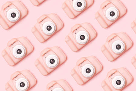 Small lovely girls pink digital camera inspired pattern. Minimal flat lay monochromatic arrangement against baby pink background.の写真素材