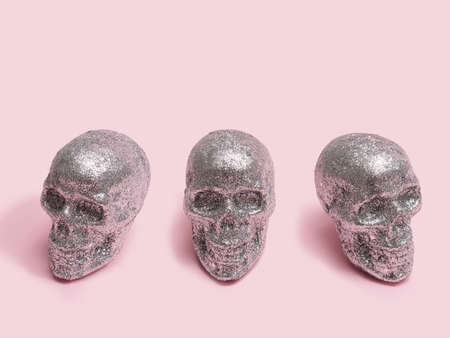 Arrangement made of three sparkling gliter covered skulls. Minimal baby pink creepy background.の写真素材