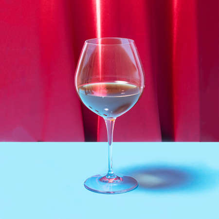 Striking crystal glass with red vine in it. Lovely red velvet and blue background.の写真素材