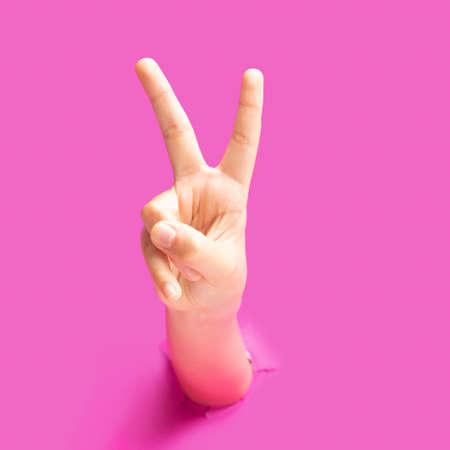 Sign of peace inspired concept. A girl hand with palm out and fingers V sign gesture.Optimistic purple in background.の写真素材