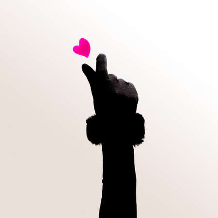 K pop concept. A girl hand with black glove and fur with two finger heart gesture. Red heart above. Minimal bright white background.の写真素材