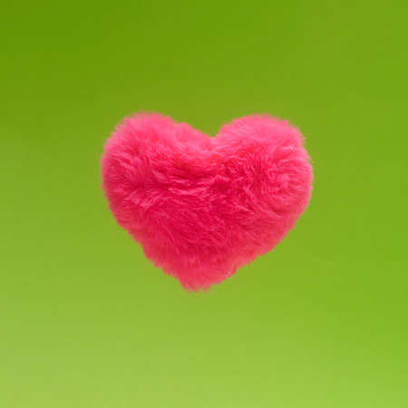 Soft love minimal concept. Fluffy pink heart against vibrant green background.の写真素材