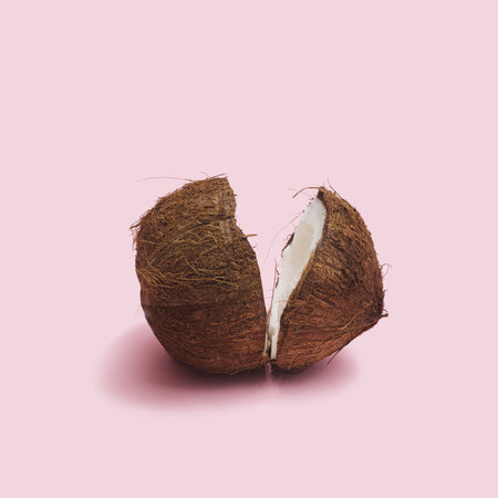 Fresh organic opened two cracked parts of the coconut head against a baby pink background. Fresh fruit, nut and seed concept.の写真素材