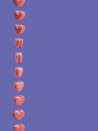 Pink heart shaped macarons rotate vertically. Creative copy space against very peri background....