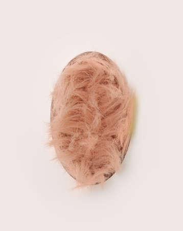 Abstract easter minimal concept. Fluffy baby pink color filled, unique egg shaped, against offwhite background.の写真素材