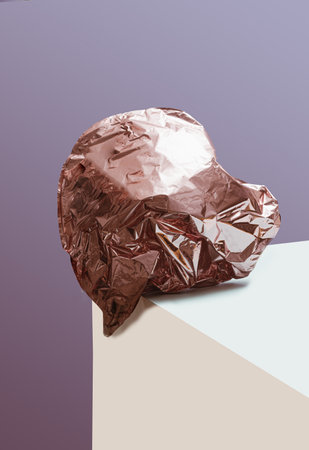 Broken heart concept. Pink heart shaped balloon crashes on the edge of pink and champagne color surfaces. Very peri purple color in background.の写真素材