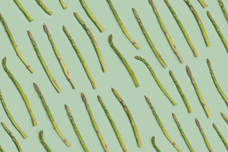 Superfood vegetarian minimal concept. Flat lay arrangement of fresh organic asparagus vegetable against pastel green backgroundの写真素材