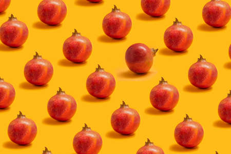 BeautifulÂ mediterranean fruit concept. Broken pattern made of many organicÂ fresh pomegranate fruits against a pastelÂ orange background.の写真素材