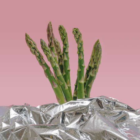 Vegan minimal superfood concept. Bunch of fresh organic asparagus vegetable against pink and silver backgroundの写真素材
