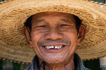 Portrait of friendly senior asian adult man with straw hatの写真素材