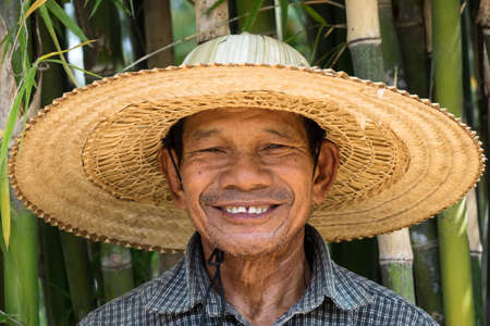 Portrait of friendly senior asian adult man with straw hatの写真素材