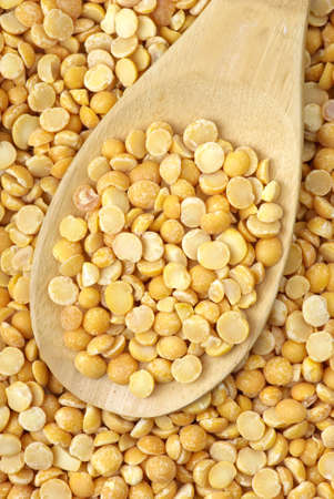 Background of split dried pea and wooden spoon filled with grainsの写真素材