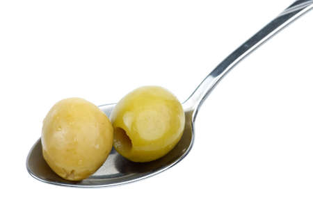 Two marinated pitted green olives in the small metal spoon isolated on the white backgroundの写真素材