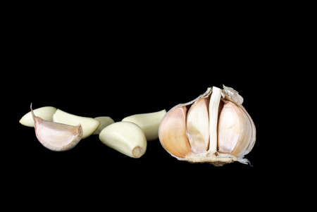 Half of garlic bulb and cloves over the black backgroundの写真素材