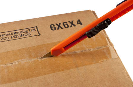 box cutter being used to open a cardboard containerの写真素材