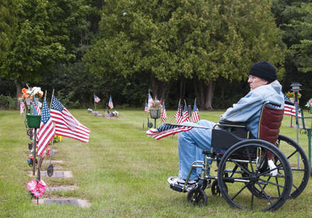 disabled veteran in a wheelchair at the cemetary remembering his fallen brothersの写真素材