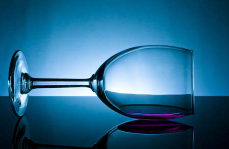 wine glass tipped on its side with refllection on blueの写真素材