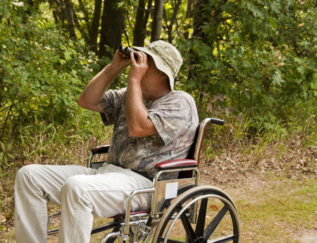 disabled man in a wheelchair watching for birds with a pair of binoculars