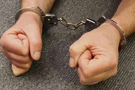mans hands locked in a pair of handcuffs