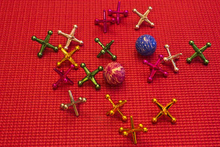 child's jacks and balls on a red rubber mat